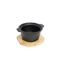 Black ceramic pot on a wooden serving board