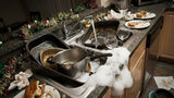 Dirty kitchen sink with pots, pans, and dishes in a cluttered kitchen.