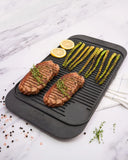 Black grill mat with grilled meat and asparagus on a marble surface