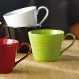 Three mugs in red, black and white on a wooden surface.