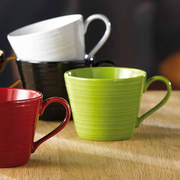 Three mugs in red, black and white on a wooden surface.