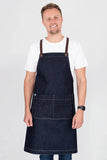A person wearing a dark blue denim bib apron with brown straps and a white t-shirt.