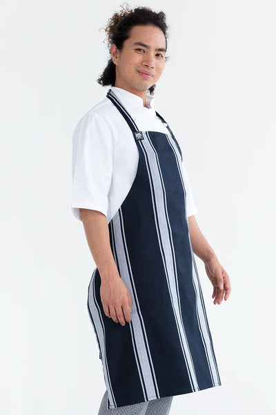 A person wearing a navy and white striped chef bib apron with adjustable neck loop over a white chef jacket.