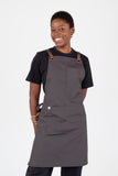 A person wearing a slate gray bib apron with leather-look press stud straps and brass-coloured eyelets.