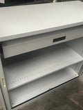 Metal storage cabinet with open shelves on a concrete floor.
