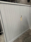 Metallic sliding door with a handle on a gray floor.