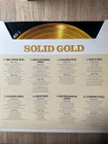 Album cover with 'Solid Gold' text and tracklist on a wooden surface