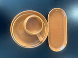 Set of ceramic bowls and a platter on a dark surface