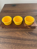Three yellow cups on a wooden board